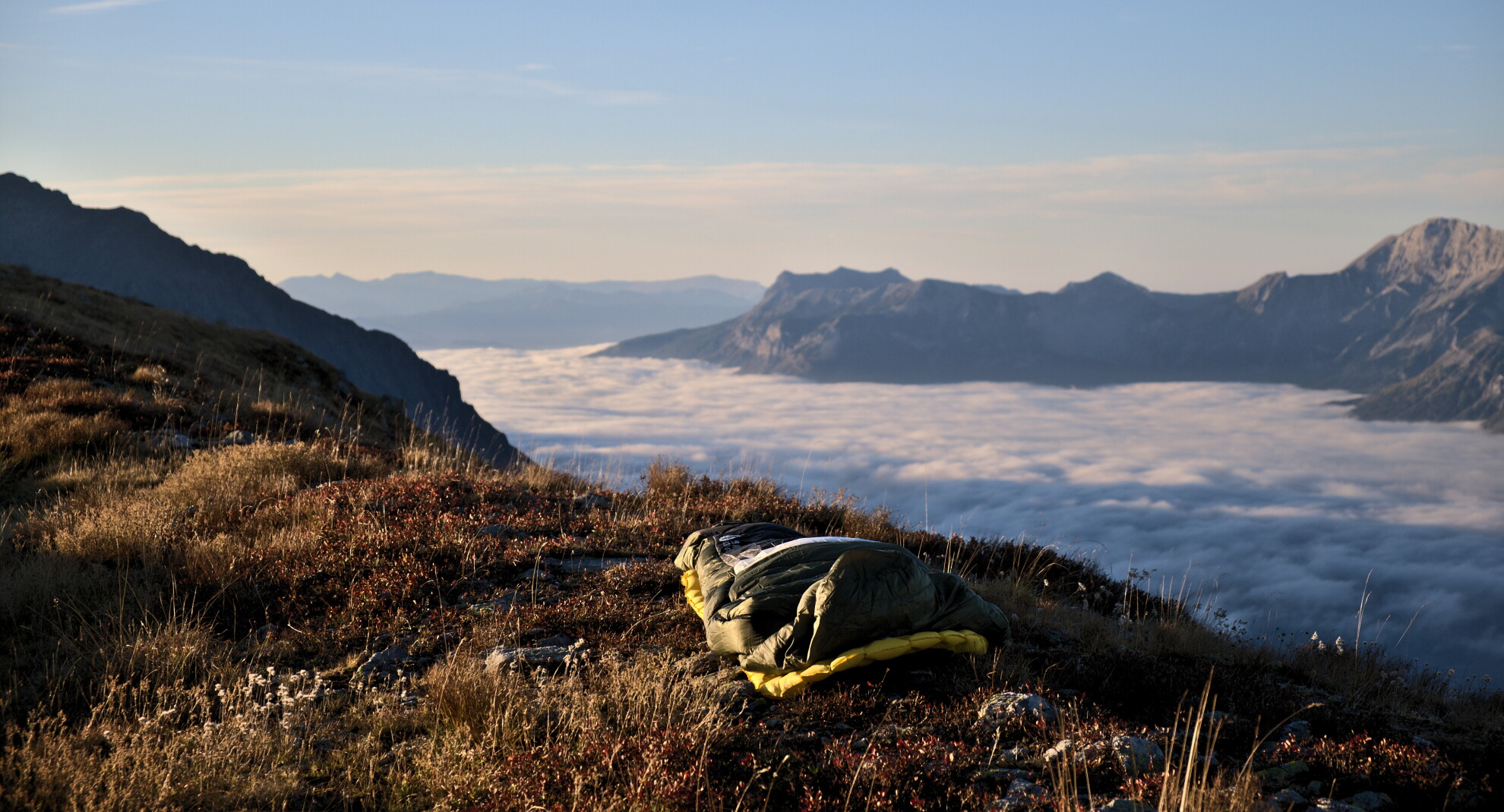 Duvet posé sur une croupe herbeuse au-dessus d'une mer de nuages